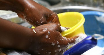 A closeup shot of a black female hand washing a yellow bowl