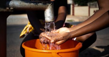 african-woman-pouring-water-recipient-outdoors_23-2149021910